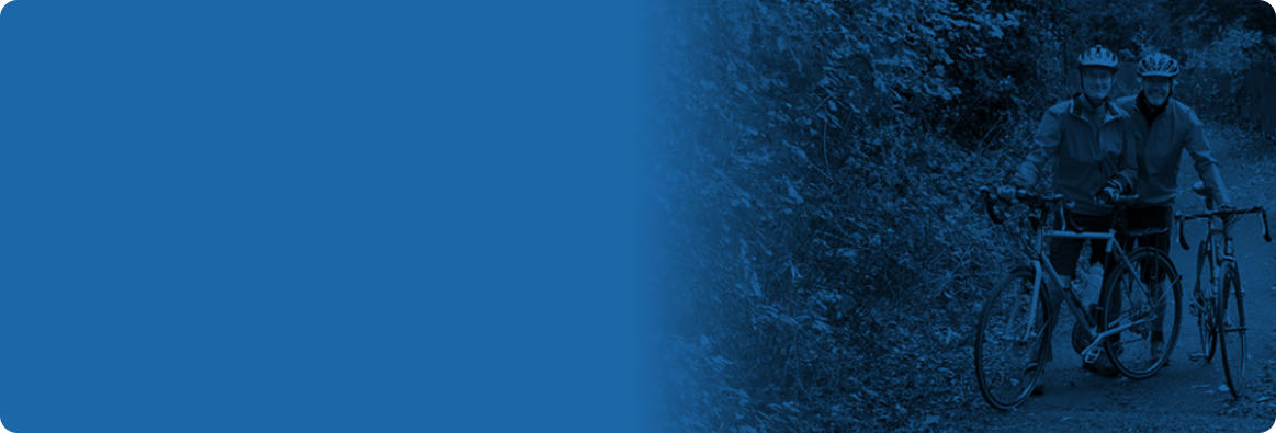 Blue banner with a photo overlayed that shows two middle-aged men standing next to their bikes on an outdoor trail.
