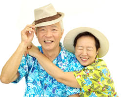 A senior couple on a white background. They are wearing Hawaiian shirts and sun hats. They're both smiling, and the woman is hugging the man with her head resting on his shoulder.